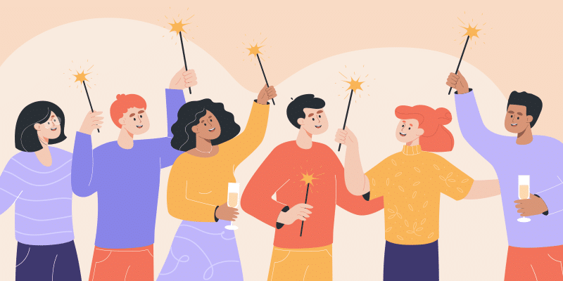 Six people smile and celebrate together, holding sparklers and glasses in a festive setting against a simple, neutral background.