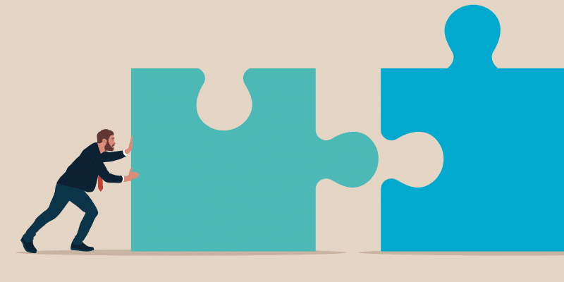 A suited man pushes a large puzzle piece toward another, representing collaboration and integration in ITSM or SaaS management platforms.