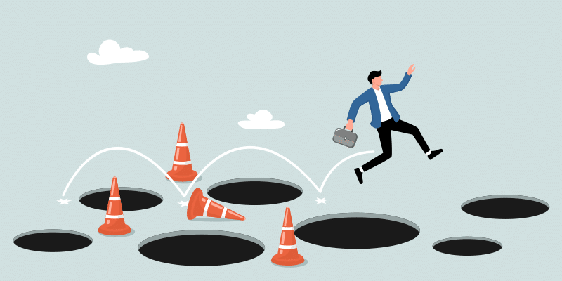 A person in a suit jumps over large holes and traffic cones, illustrating IT leaders overcoming obstacles like shadow IT challenges.